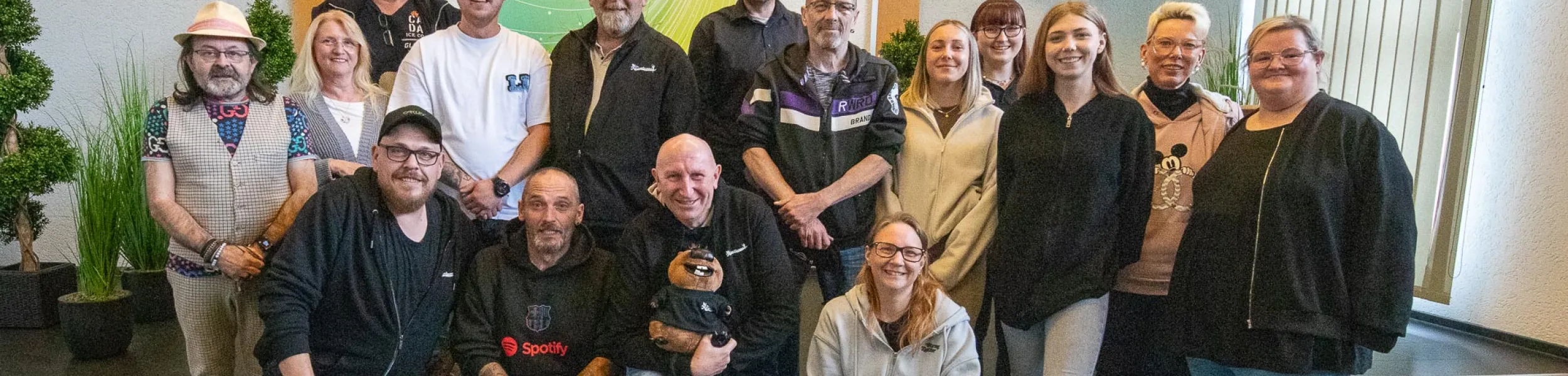 Gruppenfoto des alten und neuen Vorstands der KG Die Rosselanos e.V. in einem Innenraum. Mehrere Personen stehen und sitzen gemeinsam vor einer hellen Wand mit Fensterfront und Pflanzen im Hintergrund. Einige Vorstandsmitglieder fehlen auf dem Bild.